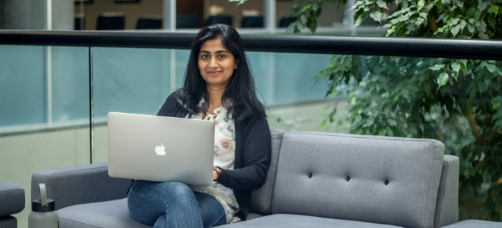 Ashita Kulkarni, a QA Engineer at Carnegie Technologies, completes some of her day's work on her laptop from a sofa in an office atrium.